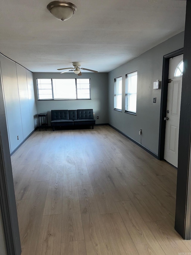 unfurnished living room featuring light wood-style flooring and a ceiling fan