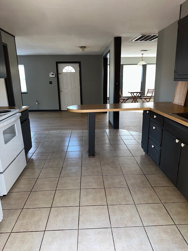 kitchen featuring white electric stove, light tile patterned flooring, a sink, visible vents, and open floor plan