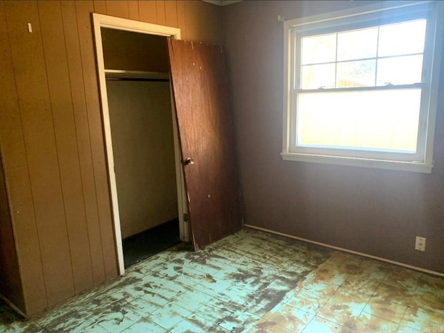860 Ash St, Prescott, AR 71857 - unfurnished bedroom featuring light floors, wooden walls, and a closet