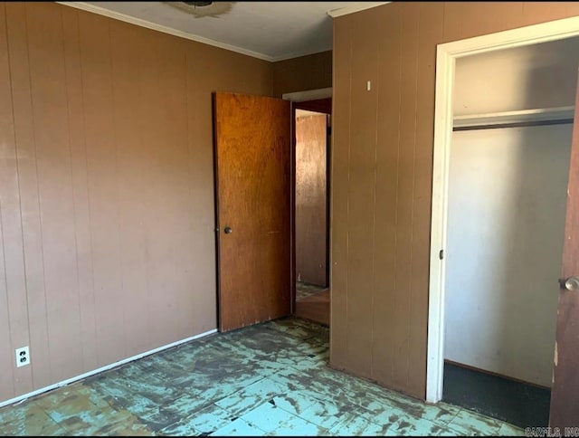 860 Ash St, Prescott, AR 71857 - unfurnished bedroom featuring wood walls, ornamental molding, a closet, and tile patterned floors