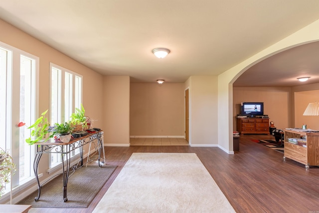 foyer entrance with arched walkways, dark wood finished floors, and baseboards