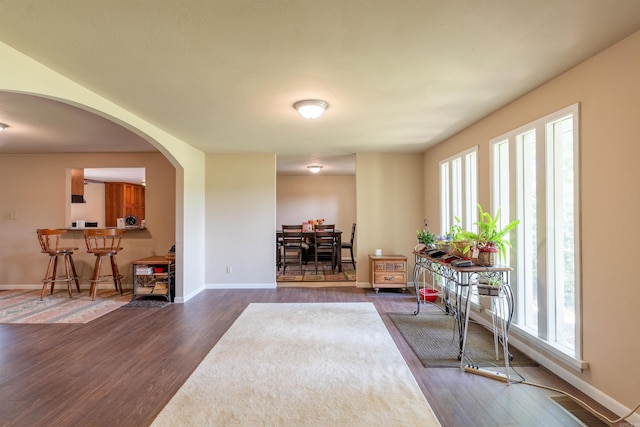 foyer entrance with arched walkways, dark wood finished floors, visible vents, and baseboards