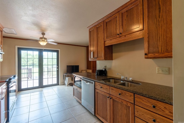 kitchen featuring brown cabinetry, dark stone countertops, stainless steel appliances, crown molding, and a sink