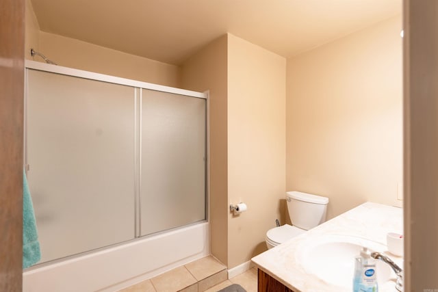 bathroom featuring toilet, combined bath / shower with glass door, vanity, baseboards, and tile patterned floors