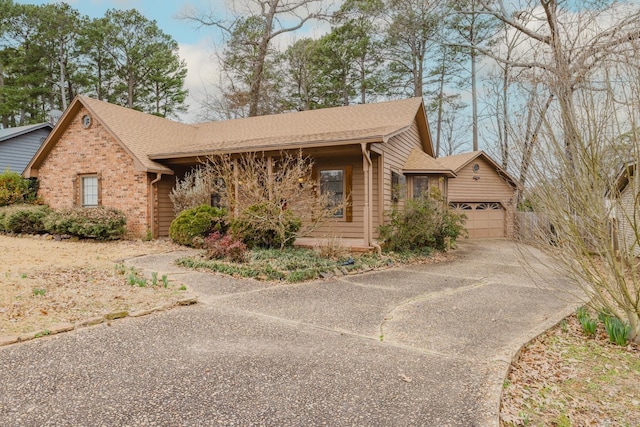 ranch-style home featuring roof with shingles, a detached garage, and brick siding