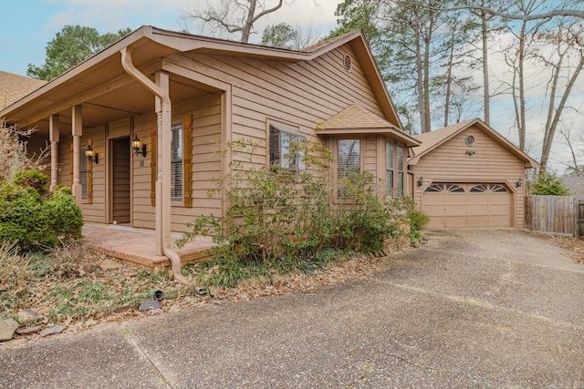 view of side of home featuring a garage, roof with shingles, and a porch