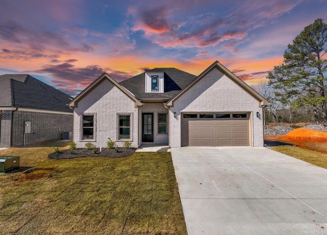 view of front of property featuring a garage, brick siding, concrete driveway, central air condition unit, and a front yard