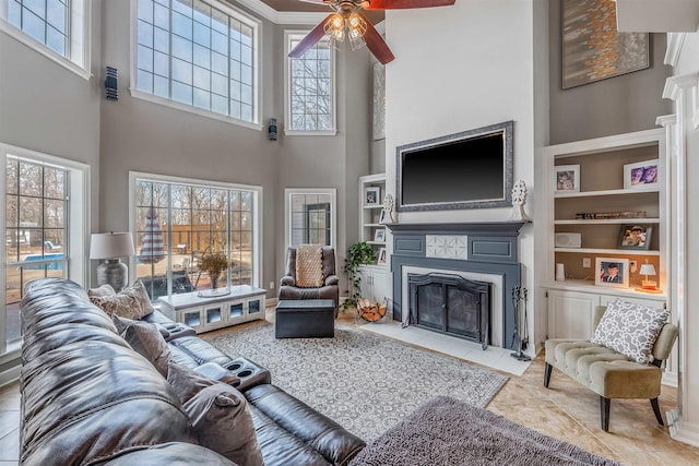 living area with built in shelves, ceiling fan, and a fireplace with flush hearth