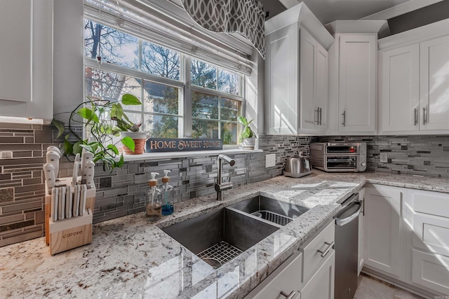 kitchen featuring a sink, white cabinetry, and light stone countertops