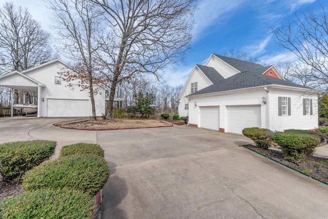 view of side of home with a garage, concrete driveway, and roof with shingles