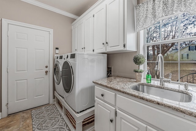 washroom with cabinet space, stone finish floor, ornamental molding, independent washer and dryer, and a sink