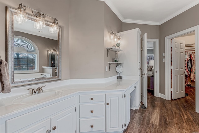 full bath with crown molding, a walk in closet, a sink, and wood finished floors