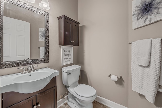 bathroom featuring baseboards, vanity, and toilet