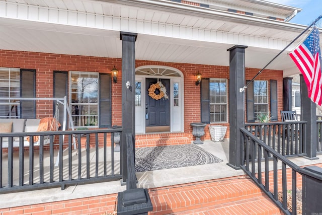 view of exterior entry with covered porch and brick siding