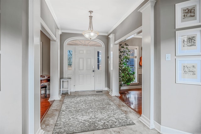 foyer entrance with baseboards, decorative columns, and crown molding