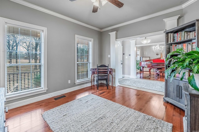 living area featuring baseboards, ceiling fan with notable chandelier, wood finished floors, and crown molding