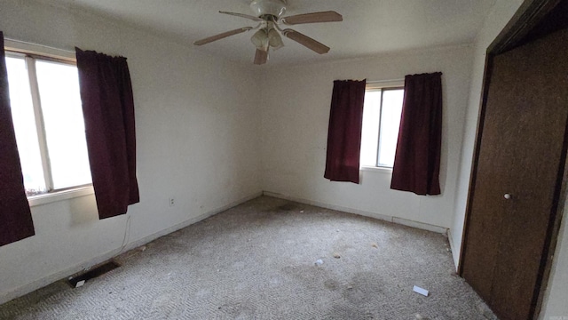 spare room with a ceiling fan, visible vents, and light colored carpet