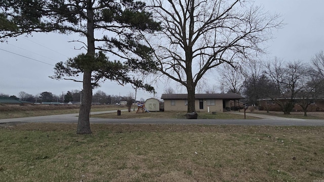 view of yard featuring driveway and a shed