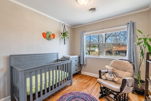 bedroom with baseboards, light wood-style floors, visible vents, and crown molding