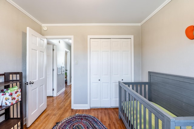 bedroom featuring crown molding, a closet, baseboards, and wood finished floors