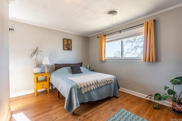 bedroom with ornamental molding, wood finished floors, and baseboards