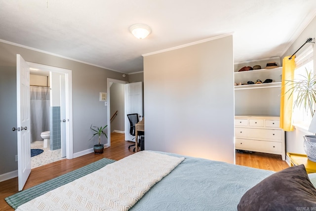 bedroom featuring light wood-style floors, baseboards, crown molding, and ensuite bathroom