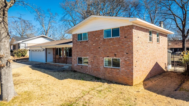 view of side of property featuring a garage, driveway, brick siding, and covered porch