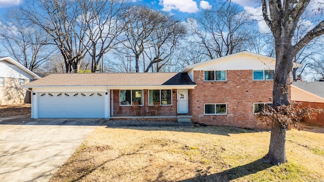 split level home with a garage, a front yard, concrete driveway, and brick siding