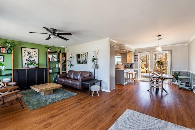 living room with ornamental molding, ceiling fan, and wood finished floors