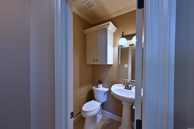 half bathroom with baseboards, visible vents, toilet, crown molding, and a sink