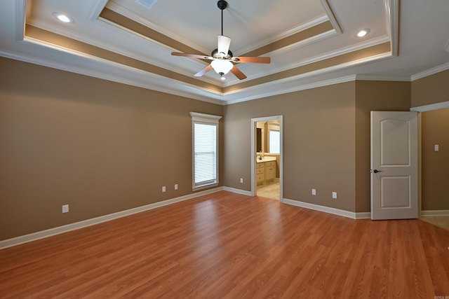 unfurnished bedroom with light wood finished floors, baseboards, a raised ceiling, and ornamental molding