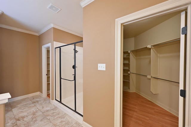 bathroom with baseboards, visible vents, a walk in closet, and ornamental molding