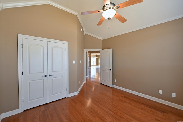 unfurnished bedroom featuring ornamental molding, lofted ceiling, baseboards, and wood finished floors