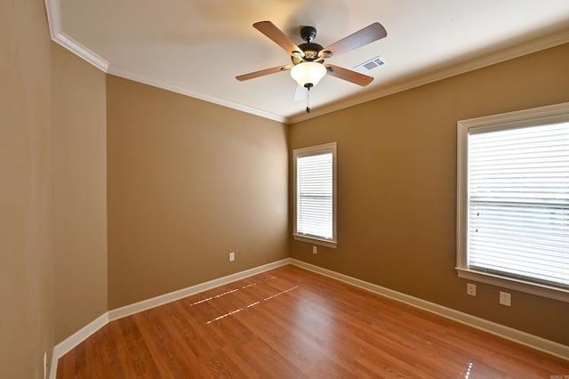 unfurnished room featuring baseboards, wood finished floors, visible vents, and crown molding