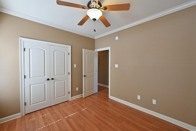 unfurnished bedroom with a closet, ornamental molding, ceiling fan, light wood-type flooring, and baseboards