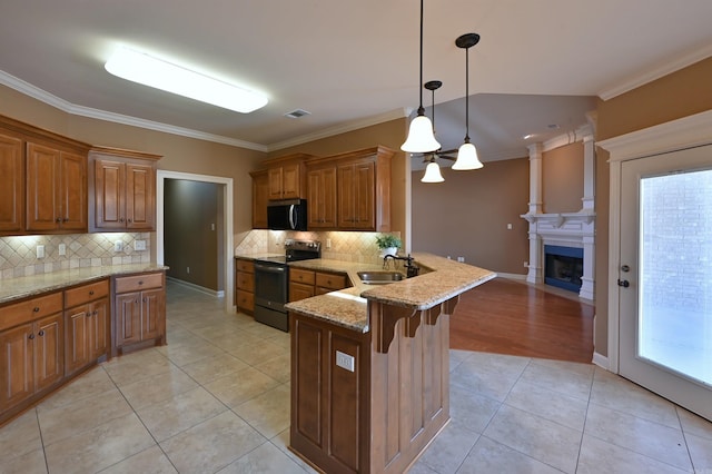 kitchen featuring a peninsula, appliances with stainless steel finishes, brown cabinets, and a sink