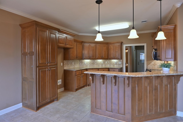 kitchen featuring light stone counters, brown cabinets, decorative light fixtures, a peninsula, and crown molding