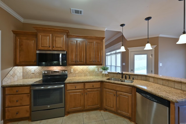 kitchen featuring pendant lighting, brown cabinets, stainless steel appliances, visible vents, and a sink