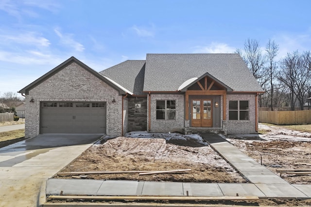 view of front of property with driveway, an attached garage, fence, french doors, and brick siding