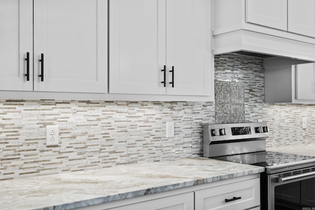 kitchen featuring light stone countertops, white cabinets, and stainless steel electric stove