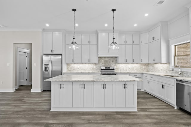 kitchen with hanging light fixtures, appliances with stainless steel finishes, a sink, and a center island