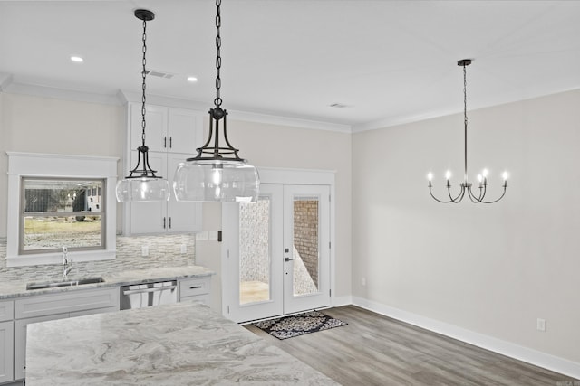 kitchen featuring dishwasher, hanging light fixtures, a sink, and white cabinets