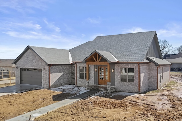 view of front facade with a garage, driveway, roof with shingles, and brick siding