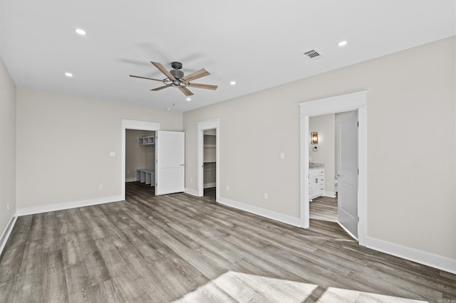 unfurnished bedroom with light wood-style floors, a walk in closet, baseboards, and recessed lighting