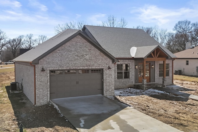 view of front facade with driveway, brick siding, central AC, and an attached garage