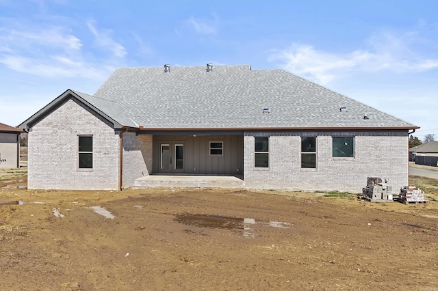 back of property with a patio, brick siding, and roof with shingles