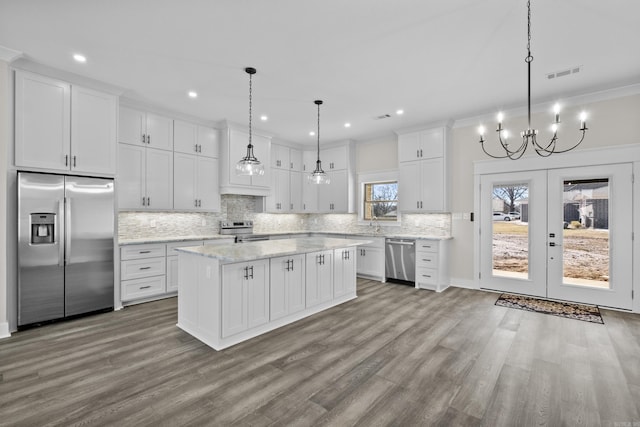 kitchen with stainless steel appliances, pendant lighting, white cabinetry, and visible vents