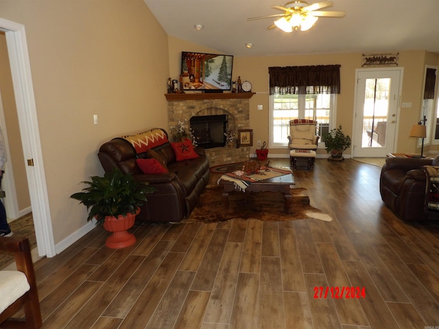 living room with a ceiling fan, a brick fireplace, vaulted ceiling, and wood finished floors