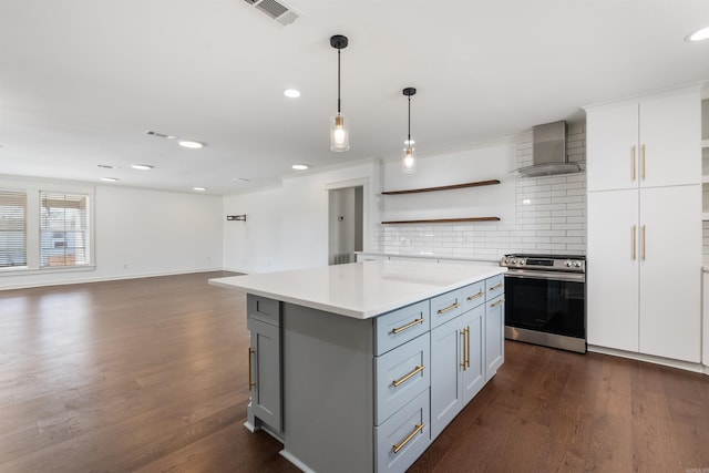 kitchen featuring visible vents, stainless steel range, light countertops, wall chimney range hood, and open shelves