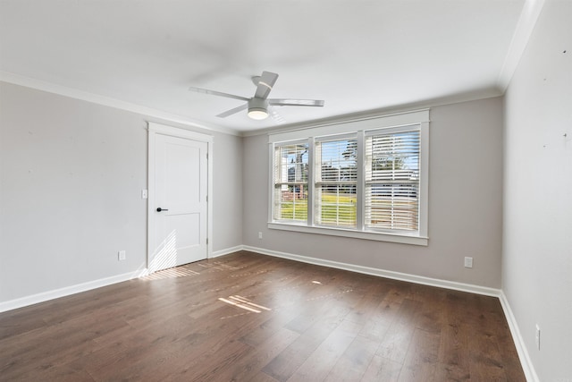 spare room featuring dark wood-style floors, ceiling fan, baseboards, and crown molding